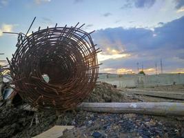 verrostete Stahlrollen in Bauprojekten. Stahl und Bambus auf Lehm- und Steinhaufen foto