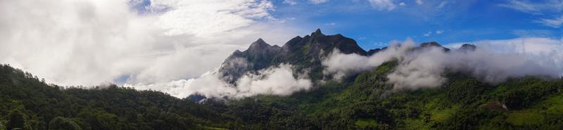 Panorama. grüne berglandschaft in den bergen liegt nebel. der Himmel ist blau und die Wolken sind weiß. foto