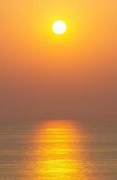 Sonnenuntergang, die Meeresoberfläche spiegelt das Sonnenlicht in Gold. klarer Himmel, orange ohne Wolken foto