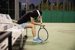 traurige Tennisspielerin, die auf dem Platz sitzt, nachdem sie ein Match verloren hat - Menschen im Sport-Tennis-Spielkonzept foto