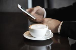 Geschäftsmann mit Handy beim Kaffeetrinken im Café - moderner Lebensstil Geschäftsmann im Café-Konzept foto