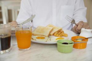 Geschäftsmann isst das amerikanische Frühstück in einem Hotel - die Leute frühstücken im Hotelkonzept foto