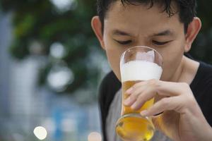 asiatischer mann, der bier im grünen gartenrestaurant trinkt - die leute entspannen sich und genießen das alkoholfreie lifestyle-konzept foto