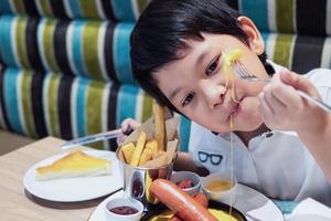 asiatischer junge, der glücklich pommes frites isst - kind mit ungesundem junk-food-konzept foto