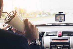 Mann, der Auto mit Navigator fährt und Kaffeetasse hält foto