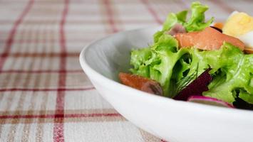 Gesunder Salat aus frischem Lachsgemüse auf weißem Teller zum Verzehr bereit - frisches, sauberes, gesundes Lebensmittelrezept für den Hintergrundgebrauch foto