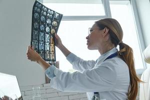 Ärztin untersucht medizinisches Röntgenbild, während sie im Büro sitzt foto