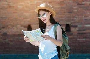 touristische reisefrau, die auf die karte schaut, während sie am bahnhof spazieren geht - straßenrucksack-reisekonzept foto