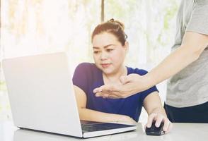 Ein Mann bildet eine Frau aus, die in einem modernen Büro mit Computern arbeitet foto