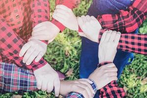 Die Menschengruppe schließt sich während ihrer Besprechungsaktivität als Symbol für die Einheit der Teamarbeit an, um ihr ultimatives Ziel zu erreichen. Vintage-Ton hautnah bei Join überreicht weicher hellgrüner Gartenhintergrund foto