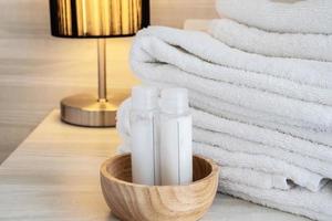 hotelhandtuch mit shampoo- und seifenflasche auf weißem bett foto