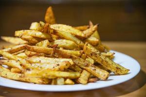 Köstliche Pommes-Kartoffel-Mischung mit kühlem Pulver auf Holztisch - traditionelles Fast-Food-Konzept foto