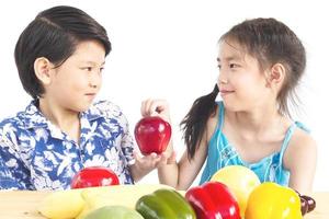 asiatische Jungen und Mädchen, die zeigen, genießen Ausdruck mit frischem, buntem Gemüse, das über weißem Hintergrund isoliert ist foto