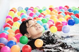 Junge, der mit buntem Ball im kleinen Swimmingpoolspielzeug spielt - fröhlicher Junge im Wasserpool-Spielzeugkonzept foto