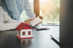 Immobilienmakler-Agent präsentiert und berät den Kunden bei der Entscheidungsfindung, unterzeichnet den Versicherungsvertrag, das Hausmodell, das Hypothekendarlehensangebot für und die Hausversicherung. foto