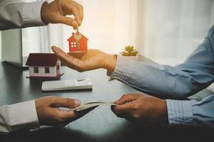 immobilienmakler, der seinem kunden nach unterzeichnung des vertrags den hausschlüssel hält, konzept für geschäftsdarlehen, investitionshypotheken, immobilien, umzug oder miete.