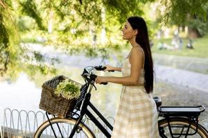 junge frau mit blumen im korb des elektrofahrrads foto