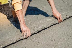 arbeiter er benutzt kelle und nivelliert beton auf dem boden des gebäudes. betonplatte gießen foto