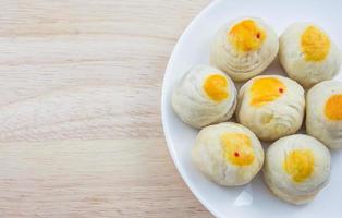 Chinesisches Gebäck Mungobohnen oder Mondkuchen mit Eigelb auf Teller und Holztisch foto