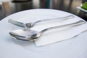 Löffel und Gabel mit weißer Platte auf dem Tisch foto