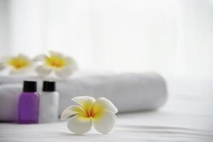 Hotelhandtuch und Shampoo- und Seifenbadflasche auf weißem Bett mit Plumeria-Blume dekoriert - Relax-Urlaub im Hotel-Resort-Konzept foto