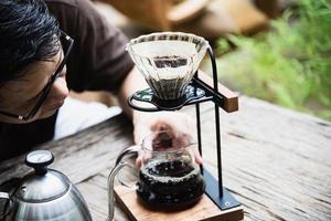 Mann, der frischen Kaffee im Vintage-Café mit grünem Naturhintergrund macht - Menschen mit frischem Kaffee im Naturkonzept foto