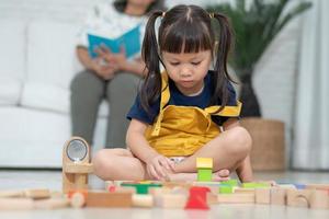 süßes asiatisches kleines mädchen, das mit bunten spielzeugblöcken spielt, kinder spielen mit lernspielzeug im kindergarten oder in der kindertagesstätte. kreatives spielen des kinderentwicklungskonzepts, kleinkindkind im kindergarten. foto