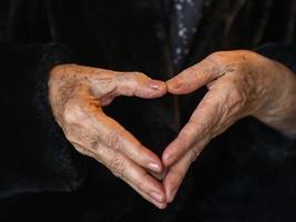 Nahaufnahme der Hände Seniorin zeigt Herzfigur mit den Fingern foto