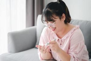 asiatische Frau mit Lanzette am Finger zur Überprüfung des Blutzuckerspiegels durch Glukosemeter, Gesundheitswesen und Medizin, Diabetes, Glykämie-Konzept foto