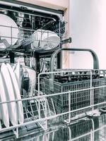 Offene Spülmaschine mit weißem, sauberem Geschirr foto