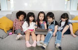 Gruppe kleiner Kinder, die gemeinsam Zeichentrickfilme auf einem digitalen Tablet ansehen