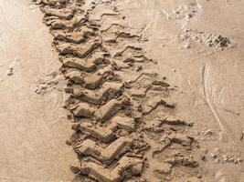 Motorradreifenspuren auf dem nassen Strandsand foto