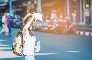 touristische reisefrau, die auf die karte schaut, während sie am bahnhof spazieren geht - straßenrucksack-reisekonzept foto