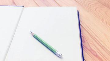 Bleistift auf weißem Notizbuch auf Holztisch foto