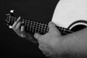 Nahaufnahme eines Mannes, der Gitarre in Schwarz-Weiß-Ton spielt foto