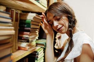 Mädchen mit Zöpfen in weißer Bluse in der alten Bibliothek. foto