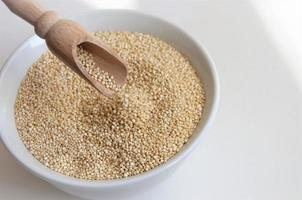 Quinoa-Samen für eine gesunde Ernährung in einem weißen Teller mit einem Löffel foto