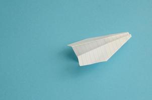 Flugzeug aus weißem Papier auf blauem Hintergrund, Minimalismus foto