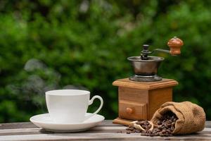 Kaffeetasse mit Mühle, dunkle Kaffeebohnen auf dem alten Holzboden, Nahaufnahme von Kaffeesamen auf natürlichem Hintergrund. foto