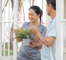 zwei Menschen mittleren Alters, die als Hobby pflanzen, Porträt. lächelnd paar person glücklich freizeit gartenarbeit im freien. reifer ehemann und ehefrau gartenbau haben einen sorglosen gesunden lebensstil, der pflanzen anbaut. foto