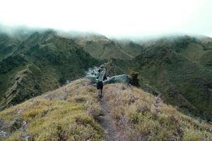 Abenteurer gehen auf wolkenverhangene Berge zu foto