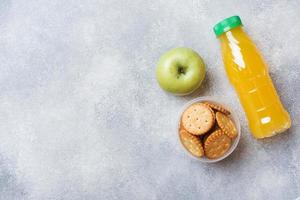 Cracker und frischer Apfel- und Orangensaft auf dem grauen Tisch. Platz kopieren. konzept schulfrühstück. foto