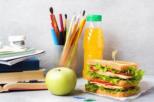 Gesundes Mittagessen für die Schule mit Sandwich, frischem Apfel und Orangensaft. verschiedene bunte Schulmaterialien. Platz kopieren. foto