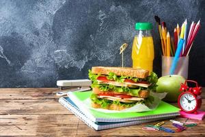 Gesundes Mittagessen für die Schule mit Sandwich, frischem Apfel und Orangensaft. verschiedene bunte Schulmaterialien. Platz kopieren. foto