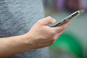 Ein Mann hält ein Telefon in der Hand und liest Nachrichten foto