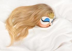 süßes blondes Mädchen schläft mit schlafender Prinzessin Plüschmaske foto