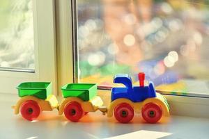 Plastikspielzeugzug mit Anhängern auf der Fensterbank, Erkundungs- und Reisekonzept. foto