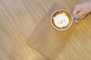 Hintergrund der schönen Frau hält eine Tasse Kaffee auf dem Holztisch. foto