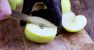 Schneiden Sie einen grünen Apfel während des Kochens auf einem Brett in die Schale foto