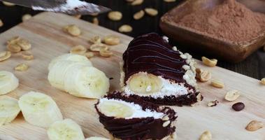 geschnittener Bananenkuchen mit Sahne in Schokolade foto